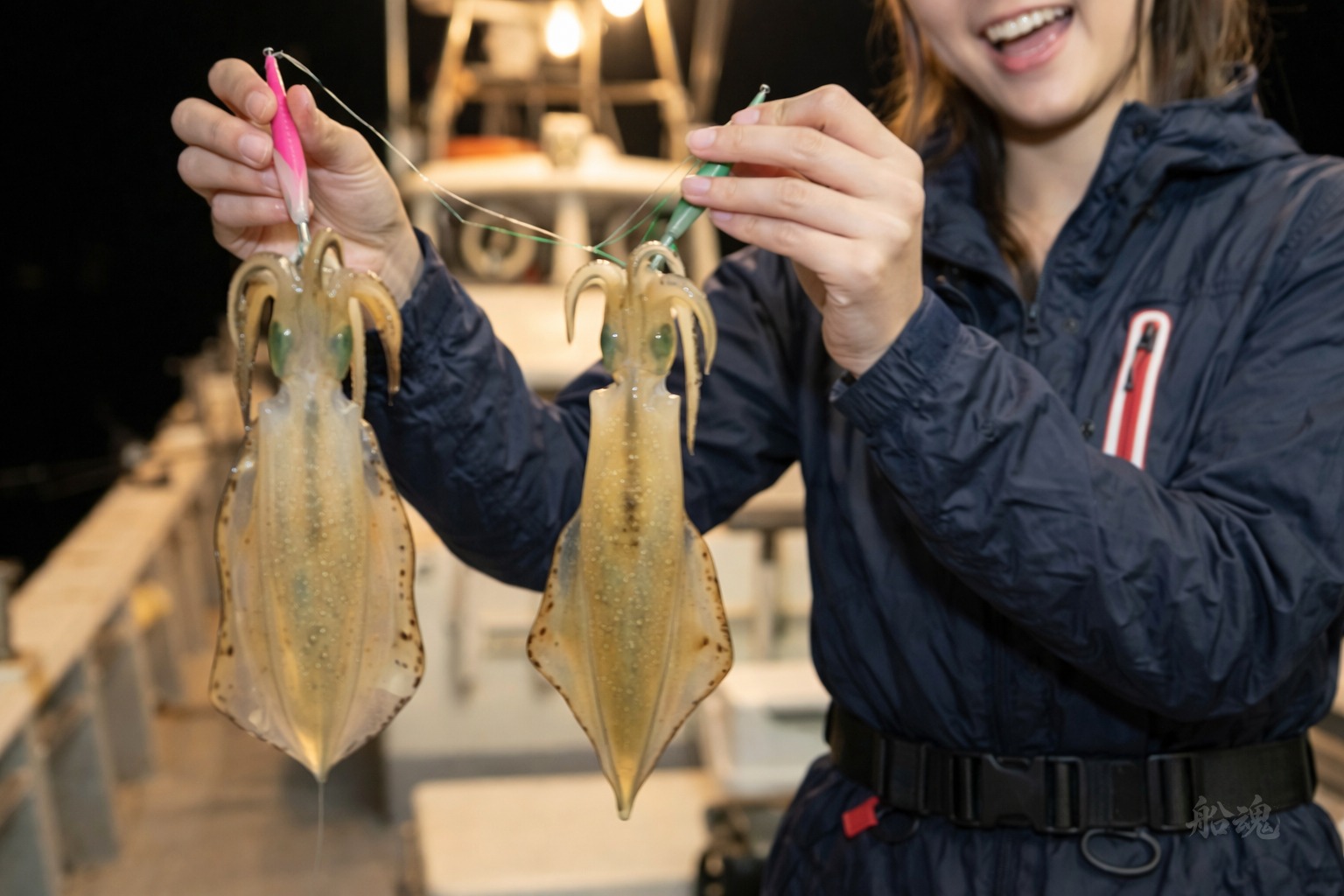 夜の船上でイカメタルの釣果を手にする様子